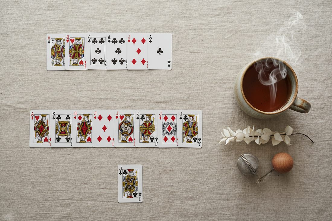 Overhead flat lay of a classic Solitaire card game on a warm linen surface with a steaming ceramic mug, styled for a mindful, screen-free moment.